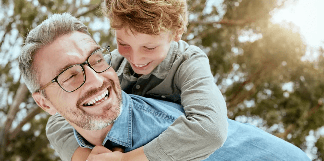 Father and son smiling, father wearing glasses